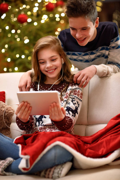 Brother and sister enjoy in Christmas eve with music from tablet - Valokuva, kuva