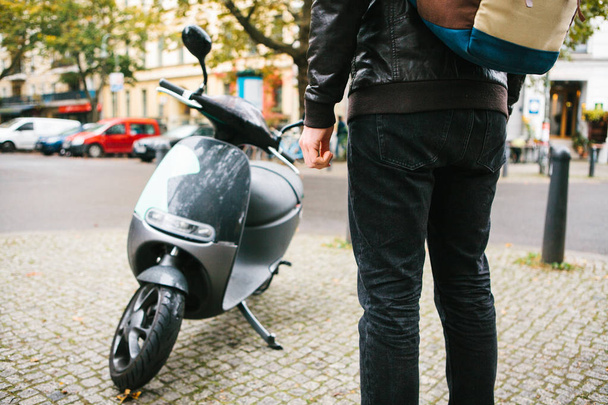 Турист собирается использовать электрический скутер. Популярный автомобиль в городе. На заднем плане улица в Берлине
. - Фото, изображение