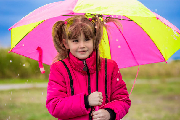 Забавная милая девушка с красочным зонтиком играет в саду
 - Фото, изображение