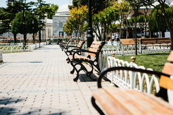 Bänke im sonnigen Park mit Gassen vor dem Hintergrund von Bäumen. Sultanahmet-Platz in Istanbul. öffentlicher Raum. - Foto, Bild