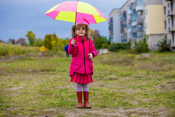 Funny cute girl with colorful umbrella playing in the garden - Photo, Image