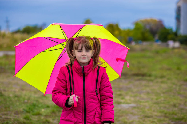 Grappige schattig meisje met kleurrijke paraplu spelen in de tuin - Foto, afbeelding