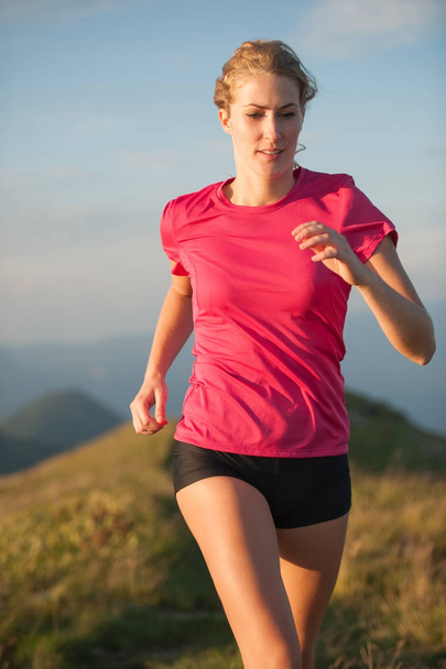 Woman runs on a top of the mountains with mountain range in back - Foto, Imagen