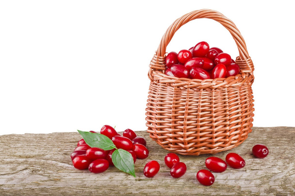 kornoelje berry met blad in rieten mand op houten tafel met witte achtergrond - Foto, afbeelding