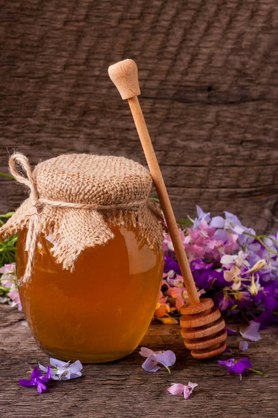 Tarro de miel con flores silvestres sobre fondo de madera vieja
 - Foto, Imagen