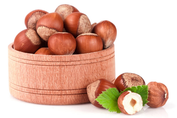 Lískové ořechy s listy v dřevěné misce izolovaných na bílém pozadí - Fotografie, Obrázek
