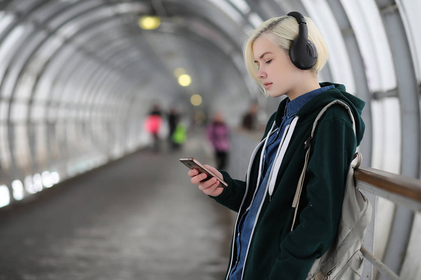 Young girl listens to music in big headphones in the subway - Fotó, kép