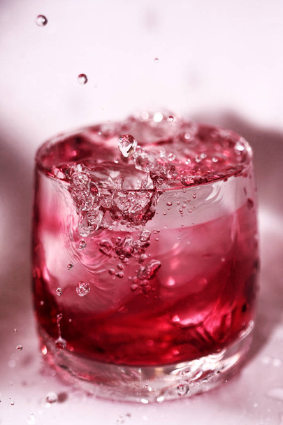 Spatten en daalt in het glas rode water - Foto, afbeelding