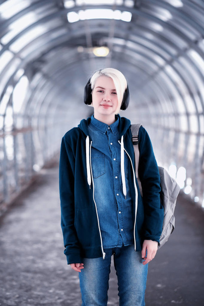 Young student listening to music in big headphones in the subway - Photo, Image