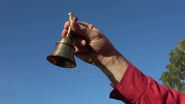Brass bell in hand on sky background  - Footage, Video