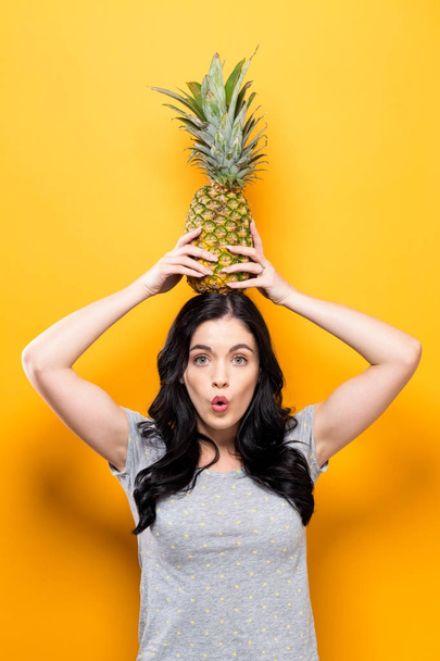 Happy young woman holding a pineapple  - Zdjęcie, obraz