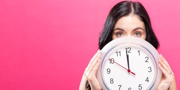 Woman holding clock showing nearly 12 - Foto, imagen