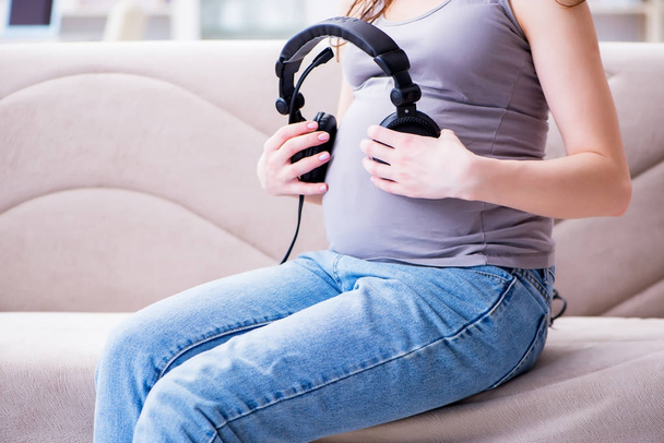 Těhotná žena s břichem bříškem sedí na pohovce doma - Fotografie, Obrázek