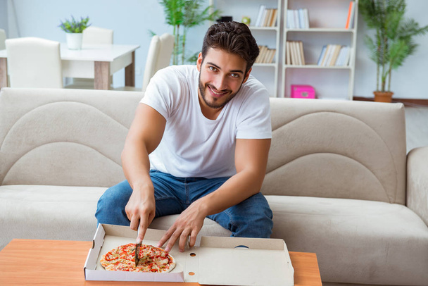 Man eating pizza having a takeaway at home relaxing resting - Foto, afbeelding