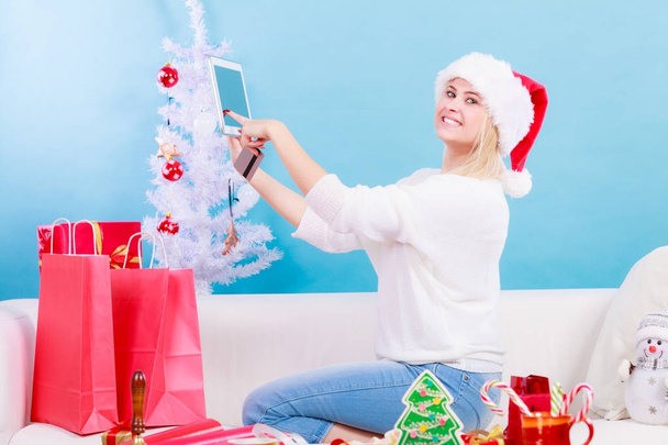 Woman in Santa hat holding tablet and credit card - Photo, image