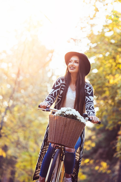 Happy active woman riding bike bicycle in fall autumn park - Foto, imagen