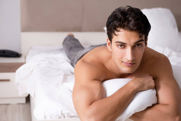 Young handsome shirtless guy showing nude torso sexy on bed at h - Фото, изображение