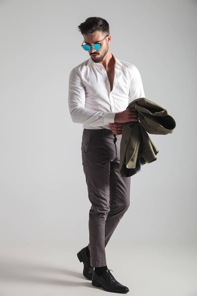 Вид сбоку молодого модного человека, крепко держащего рукав
 - Фото, изображение