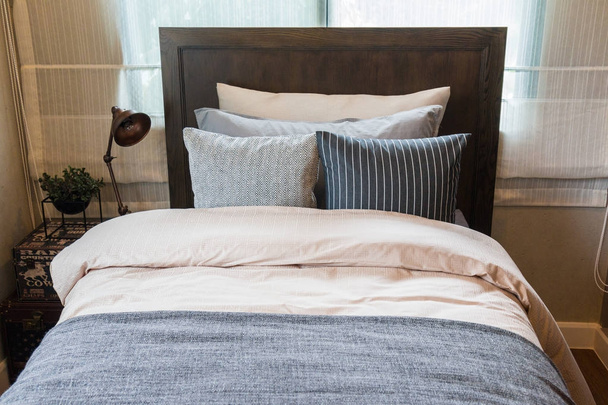 Muchas almohadas en la cama y las lámparas de cabeza de la cama con luz cálida
. - Foto, imagen