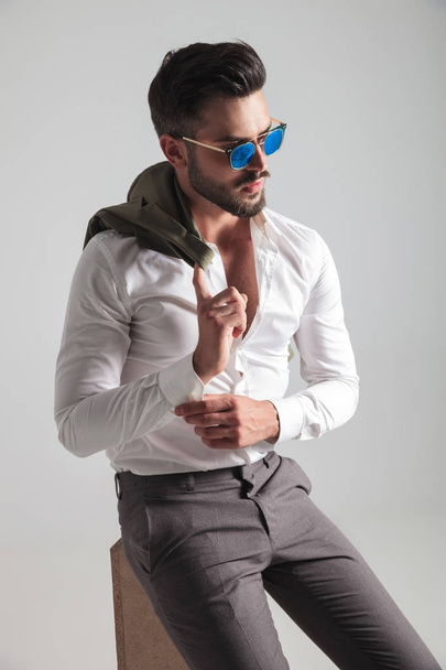 side view of a seated fashion man fixing his sleeve  - Foto, Imagem
