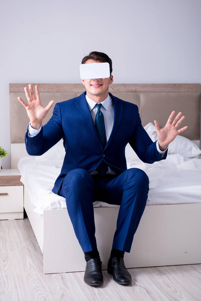 Бизнесмен в гарнитуре виртуальной реальности в спальне - Фото, изображение
