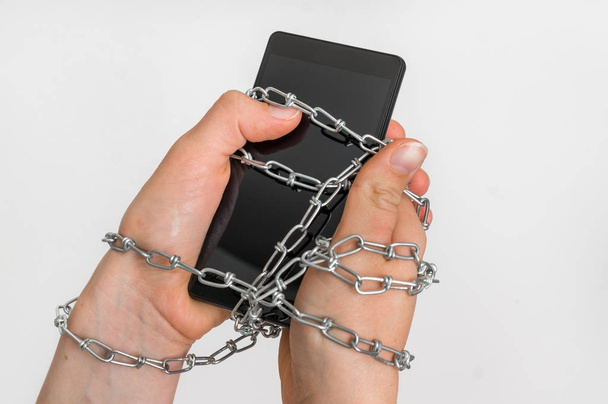 Chain ties together hands and smartphone - addiction concept - Photo, image