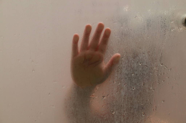 Ребенок в душе за стеклом с каплями
 - Фото, изображение