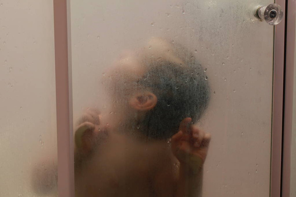Bébé dans la douche derrière le verre avec des gouttes
 - Photo, image