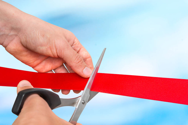 Hand with scissors cutting red ribbon - opening ceremony - Photo, Image