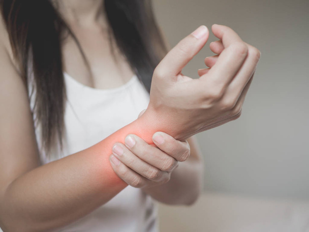 Mulher de close-up segura seu pulso lesão na mão, sentindo dor
.  - Foto, Imagem