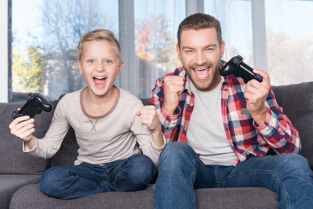 father and son playing with joysticks - Foto, Bild