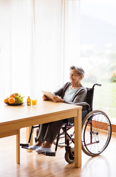 Senior woman in a wheelchair with tablet at home. - Photo, Image