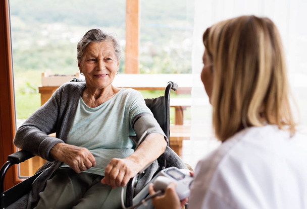 Egészségügyi látogató és egy idős nő otthoni látogatás során. - Fotó, kép