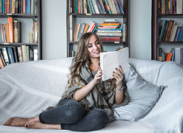 girl reading book on sofa - Foto, afbeelding