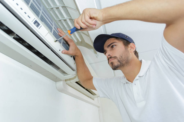 portrait of mid-adult male technician repairing air conditioner - Foto, Bild