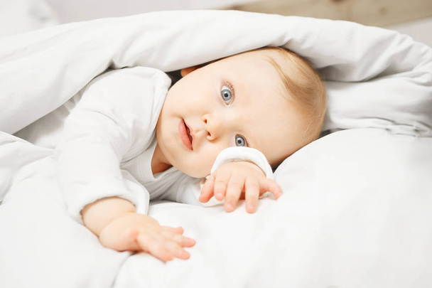 Baby lies in comfortable bed under warm blanket - Foto, Imagen