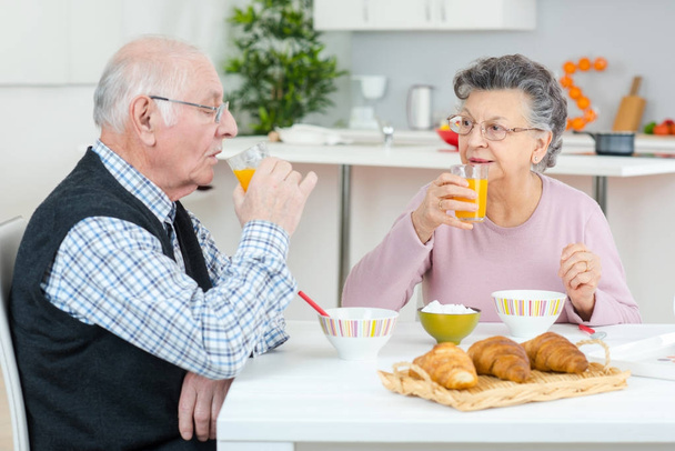 happy senior couple discussing while having breakfast at table - 写真・画像