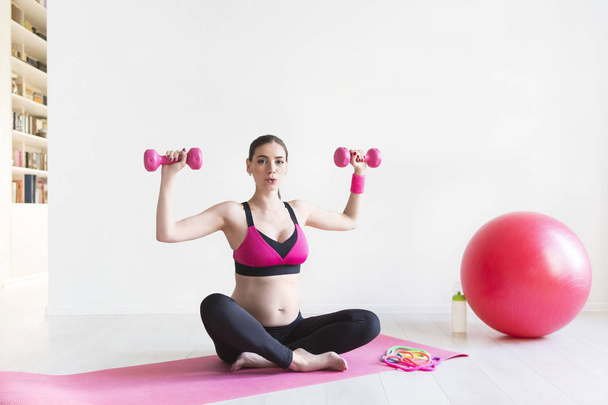 Uma jovem grávida fazendo exercícios de fitness
 - Foto, Imagem