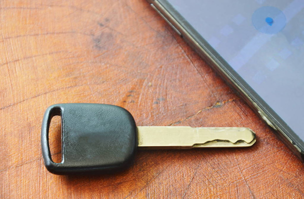  car key and smart phone opened map on wooden table - Фото, изображение