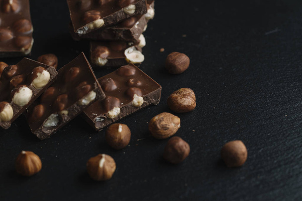 Pièces de barre de chocolat et noix sur fond d'ardoise sombre avec espace de copie. Fond chocolat. Vue de dessus. tonique
 - Photo, image