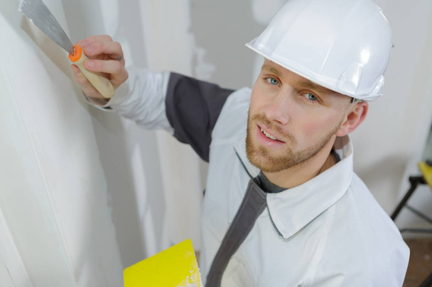 trabalhador manual com ferramentas de reboco de parede dentro de uma casa
 - Foto, Imagem