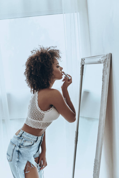 woman looking at mirror and putting on lipstick - Foto, Bild