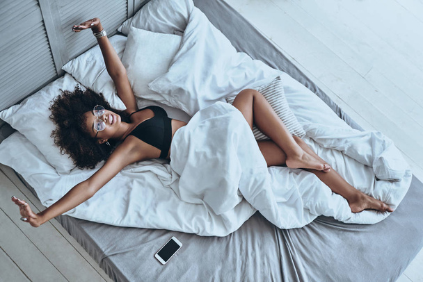 African woman lying on bed - Фото, зображення
