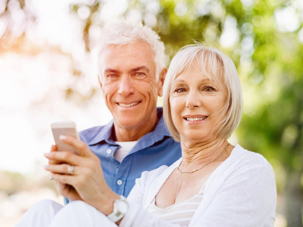Happy senior couple looking at smartphone - Фото, изображение
