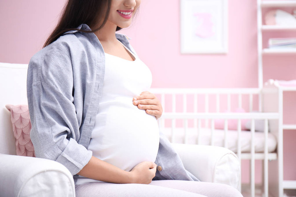 Pregnant woman sitting in baby's room - Fotó, kép