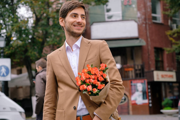 Mosolyogva gazdaság egy csomó rózsák jóképű fiatalember portréja - Fotó, kép