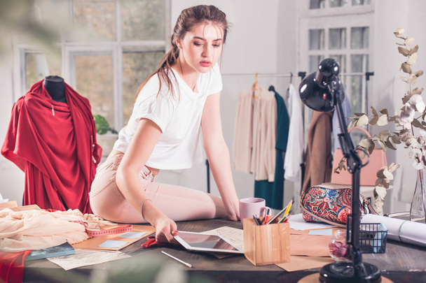 Fashion designers working in studio sitting on the desk - Fotó, kép