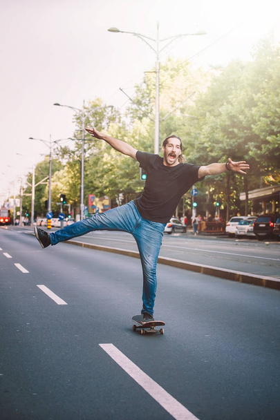 Happy and funny skateboarder ride skateboard through the city st - Фото, изображение