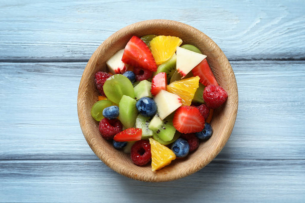 Bowl with delicious fruit salad on wooden background - Photo, Image
