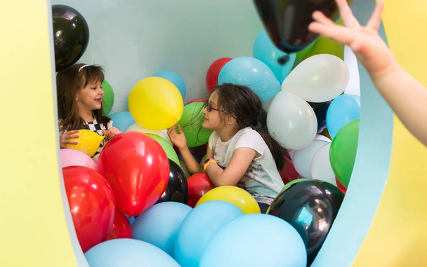 Дві милі дівчата розмовляють під час гри з різнокольоровими кульками
 - Фото, зображення